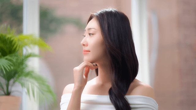 Woman lost in thought in a room with sunlight through a window