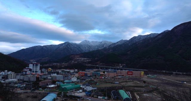 Suburban village between mountains under cloudy blue sky