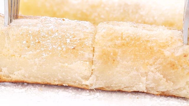 Close-up of sugar-dusted pastry rolls on a white plate