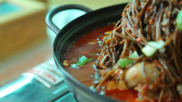 Plate of pork backbone stew topped with sweet potato stem salad