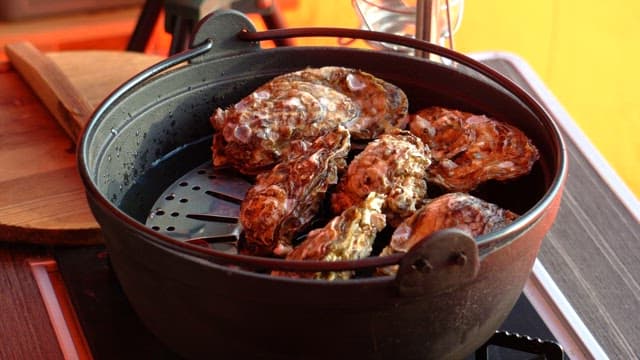 Fresh oysters prepared in a pot on a gas stove