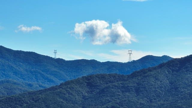 Mountain range with power lines and clouds