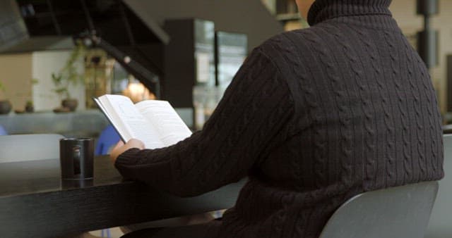 Person Reading a Book at a Modern Cafe