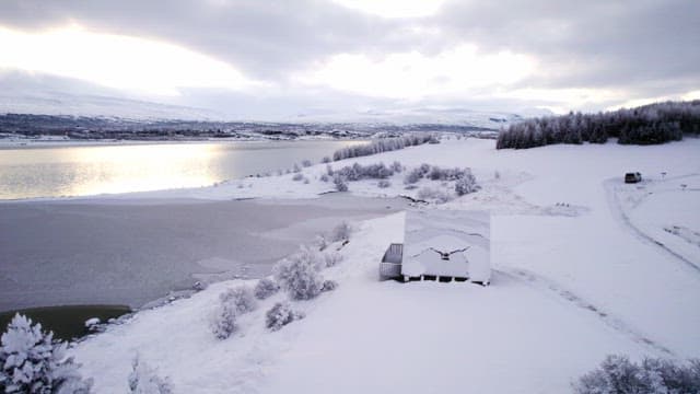 Snow-covered landscape with a cabin by a lake