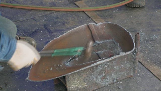 Worker shaping metal piece with a hammer