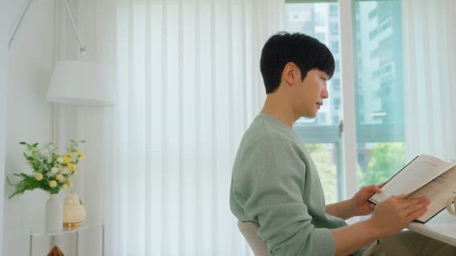 Man Reading a Book by the Window in Bright Living Room
