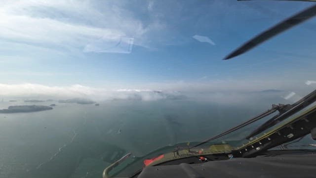 View of misty ocean and islands from a helicopter cockpit on a clear day