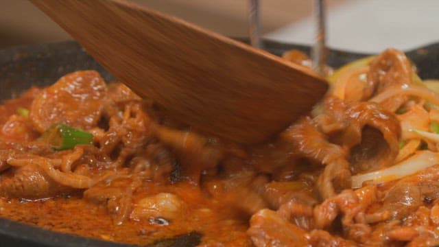 Cooking stir-fried pork with vegetables using a wooden spatula
