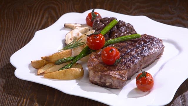 Juicy beef steak with asparagus and tomatoes in dish