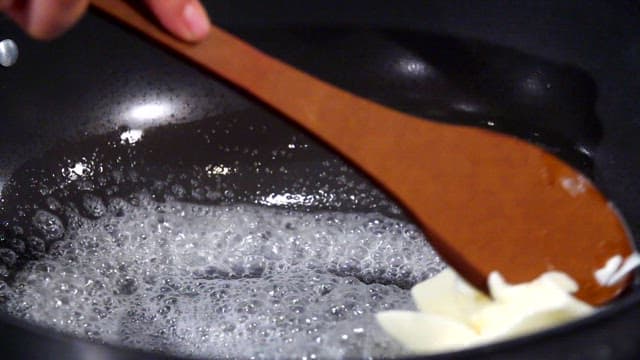 Butter melting in a pan with a wooden spatula
