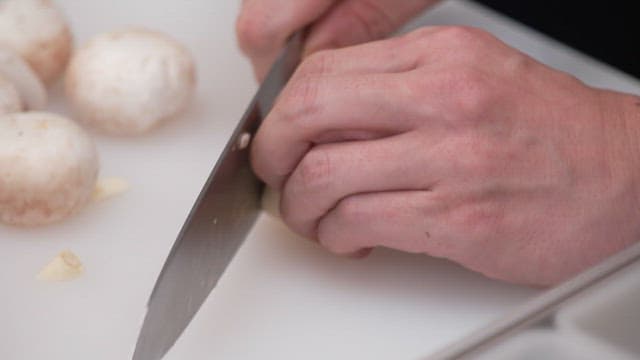 Cutting garlics with a knife on a cutting board