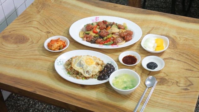 Fried rice and stir-fried meatballs and vegetables plated on a wooden table