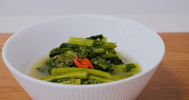 Chopsticks Picking Up Radish Kimchi in a White Bowl
