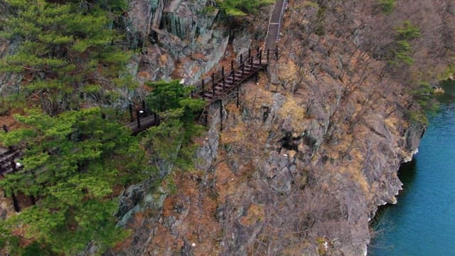Person walking along a trail on a steep rocky cliff