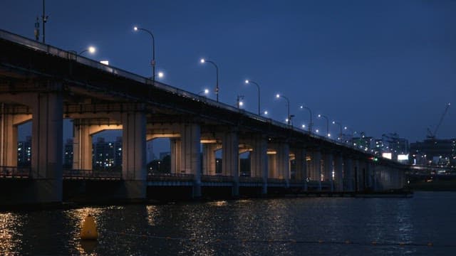Illuminated bridge over water at twilight