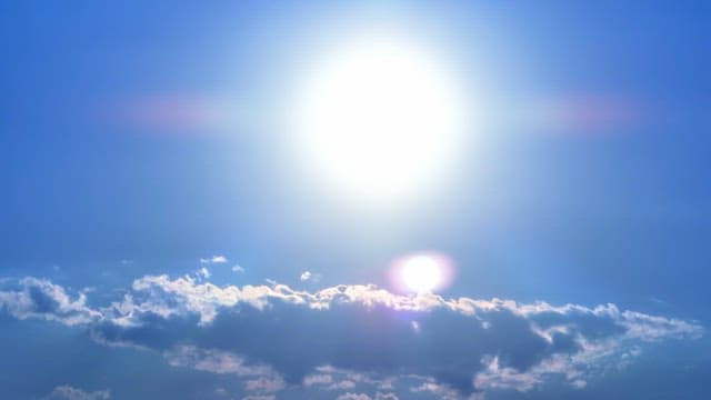 Bright sun shining over fluffy clouds