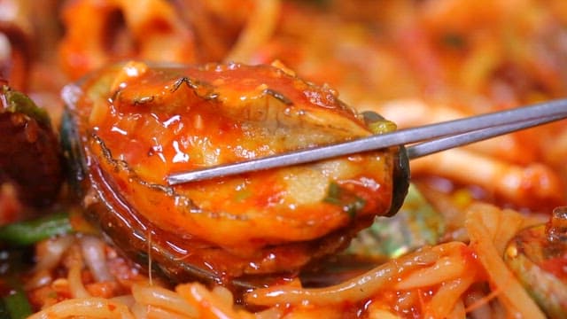 Chopsticks holding abalone in spicy braised seafood