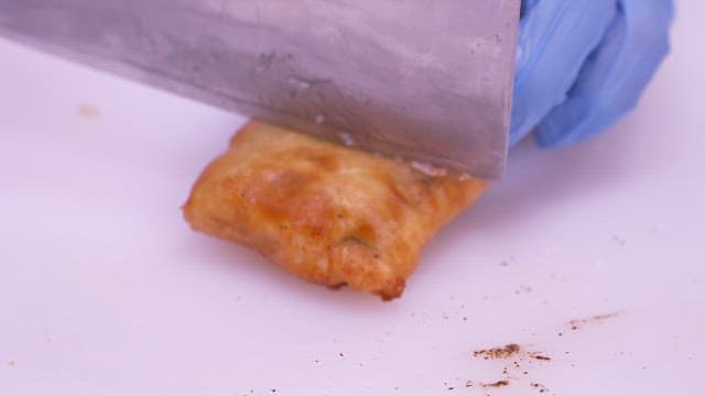 Cutting freshly fried golden-brown eel with a knife