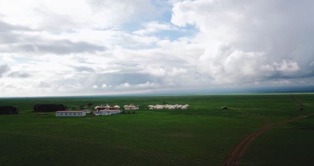 Vast green fields with scattered yurts