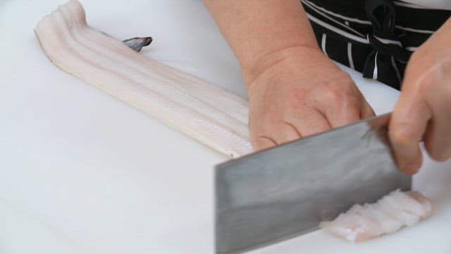 Slicing fresh conger eel on a cutting board