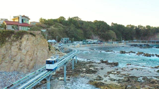 Coastal Monorail above the Rocky Shoreline with Waves on a Clear Day