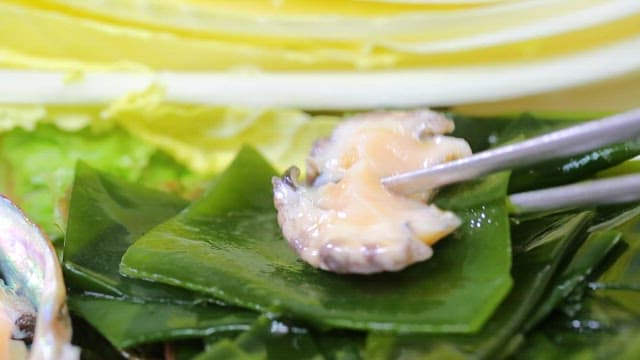 Fresh abalone on sea mustard with chopsticks