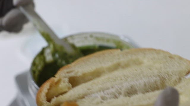 Spreading basil pesto between bread