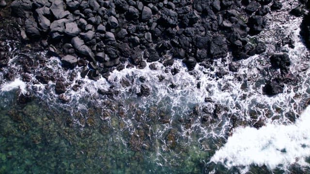 Aerial View of Waves Crashing on Rocky Shore