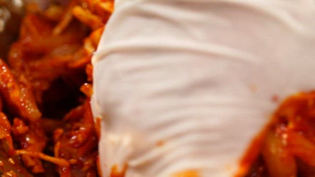 Mixing the swordtip squid and seasoning with gloved hands