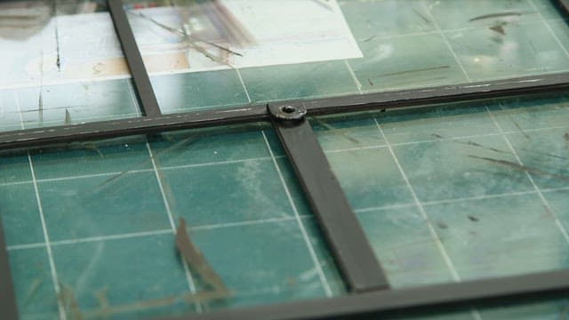 Handling a metal frame on a green grid cutting mat