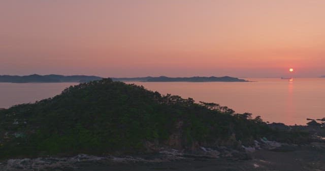 Sunset over a forested hill and sea