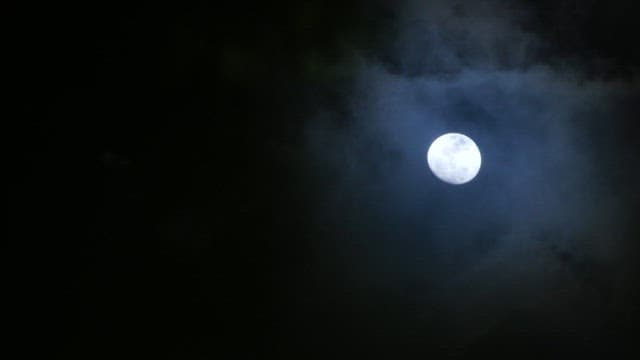 Bright moon in a cloudy night sky