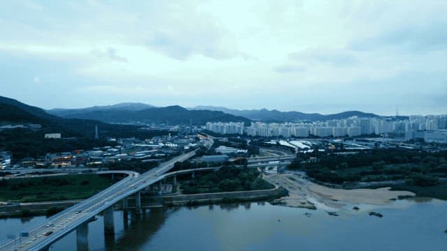 Bridge with cars passing over a river with city skyline