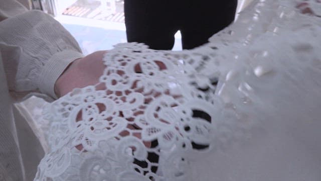 Hands examining lace fabric and bridal gown details