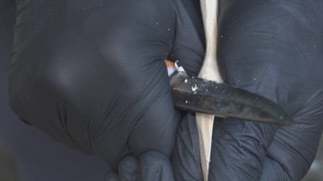 Hands carving wood with a knife