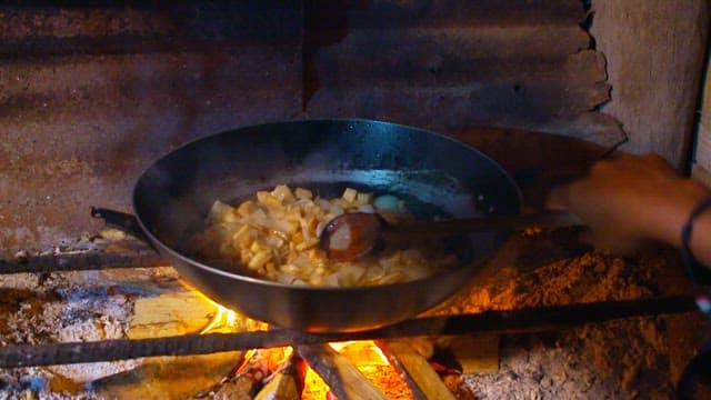 Sautéing onions and tuna in a frying pan over an outdoor fire