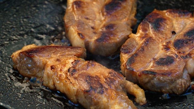 Grilling of juicy marinated pork on a hot frying pan
