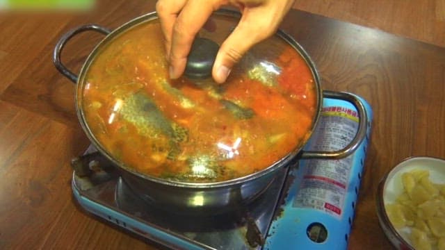 Spicy fish stew boiling on a gas burner