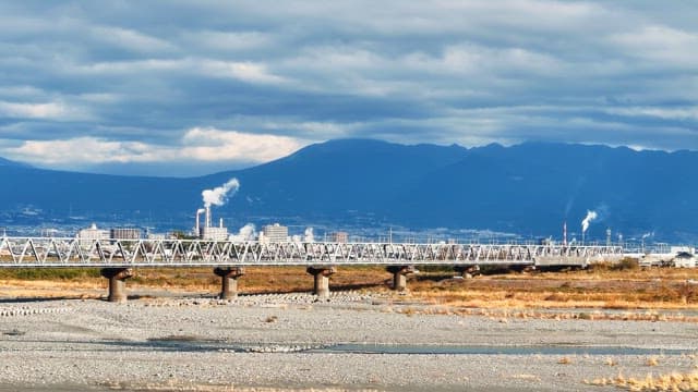 Train crossing a bridge with mountains