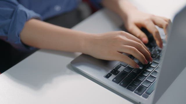 Hands typing on a laptop keyboard