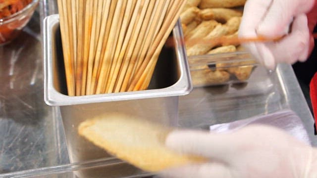 Preparing fish cake skewers with gloves