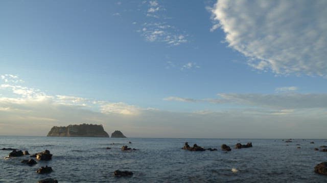 Island in the distance on a rocky ocean shore of Jeju Island