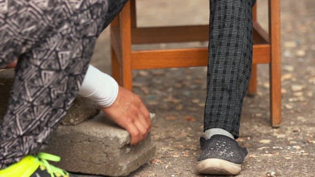 Placing stones to support the feet of a person sitting on a chair
