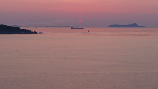 Serene sea with a distant ship at sunset
