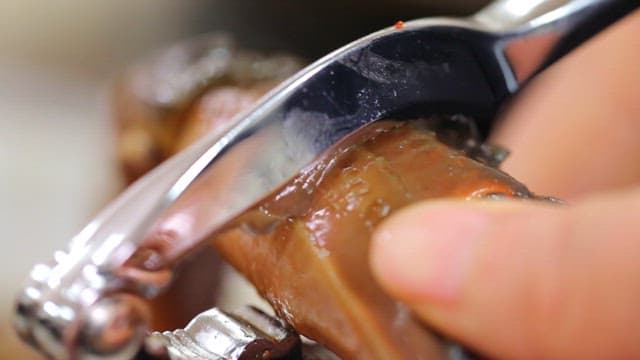 Cutting crab legs of soy sauce marinated crab with tongs