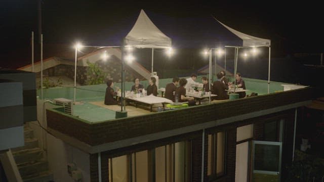 Group of people dining on the rooftop at night under lights