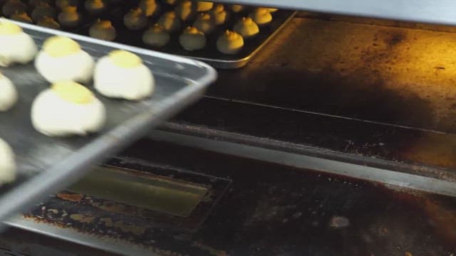 Placing trays of dough into an industrial oven in a bakery