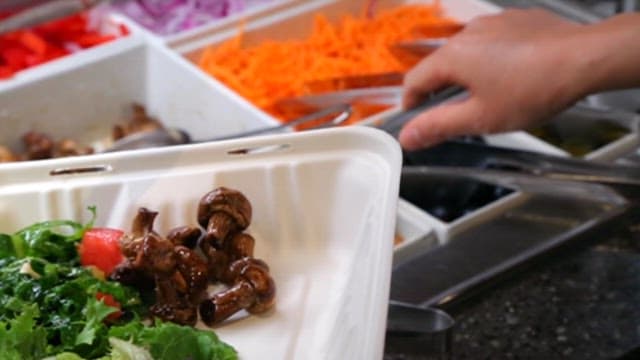 Preparing a fresh salad at a food bar
