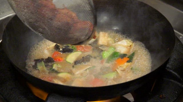 Vegetables and meatballs simmering in a pan