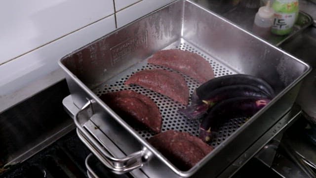 Steamed meat dumplings and eggplants in a steamer